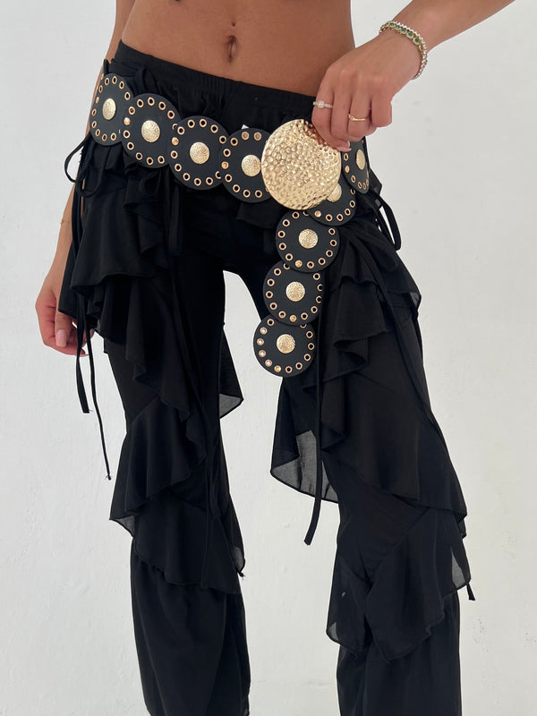 Black ruffled pants with gold embellishments on a white background