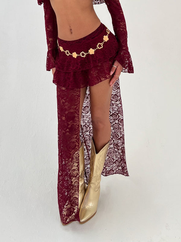 Lady wearing a burgundy skirt and gold belt and boots on a white background