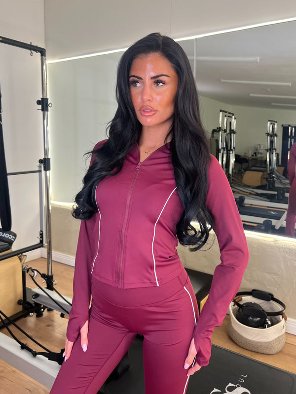 Woman in a maroon athletic outfit standing in a gym.