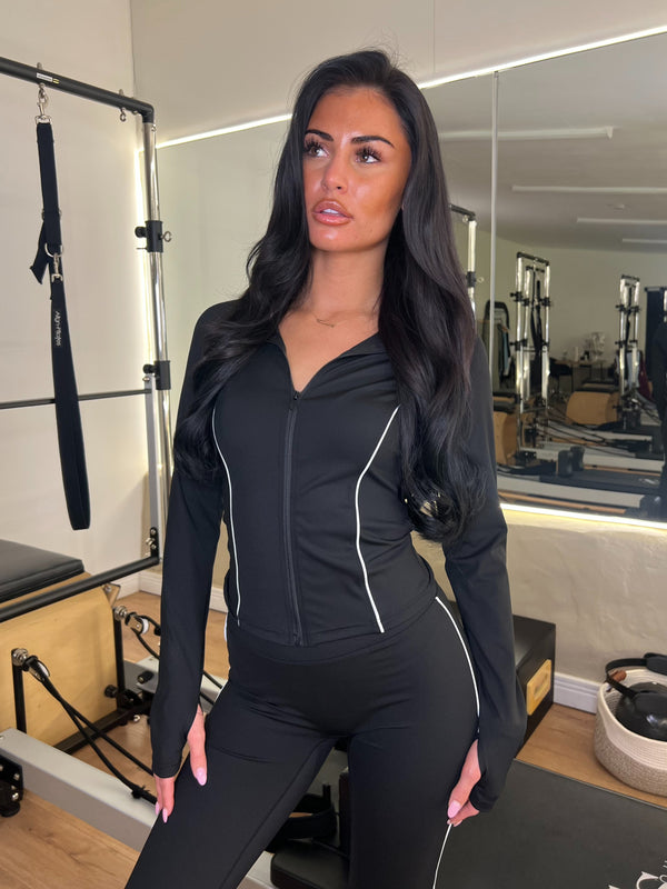 Woman in black athletic wear sitting on a bench in a gym setting