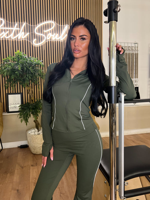 Woman in green athletic wear posing next to a pole in a room with decor elements.