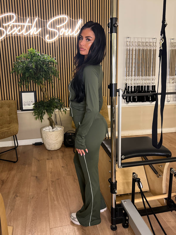 Woman in green outfit posing in a fitness studio with 'Sixth Soul' branding.
