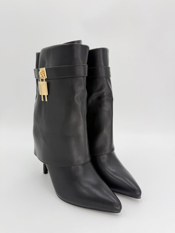 Pair of black leather boots with gold buckles on a light gray background