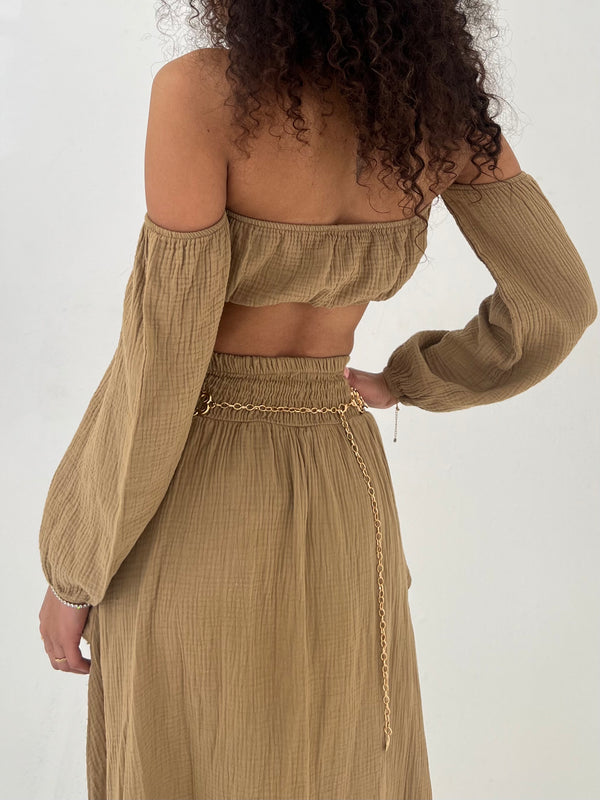 Woman wearing a camel off-shoulder top and skirt set with a white background