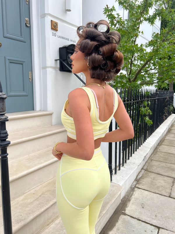 Woman in a yellow outfit standing on steps outside a building with a blue door.