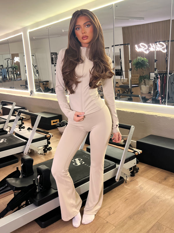 Beige Zip Jacket Wide Leg Trouser Gym Set women's athleisure set, front view in Pilates studio