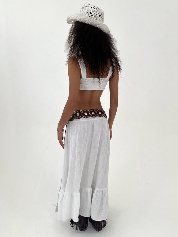 Woman wearing a white outfit , burgundy belt, and cowboy hat on a white background
