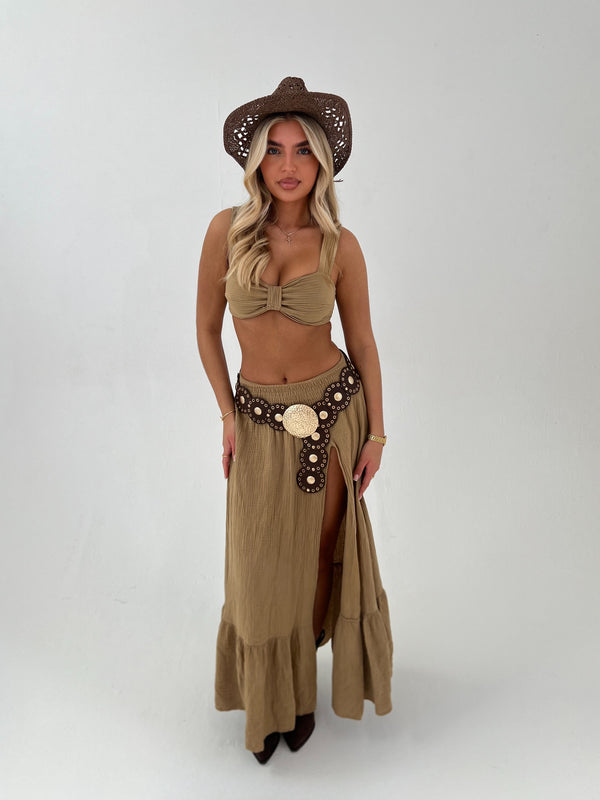 Woman wearing a beige top and skirt with a hat on a white background