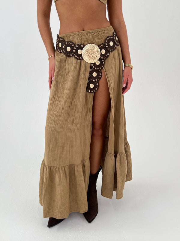 woman in a camel skirt with brown boots, belt on a white background