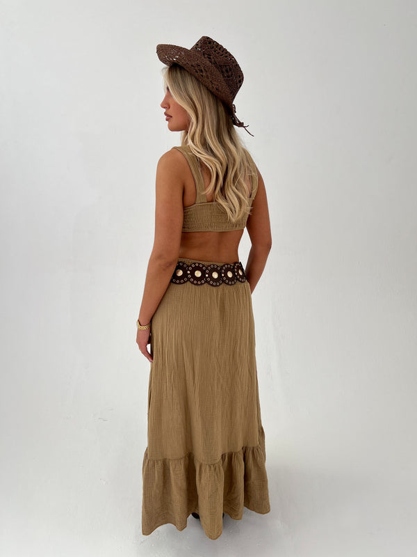 woman in a camel outfit with brown boots, belt and hat on a white background