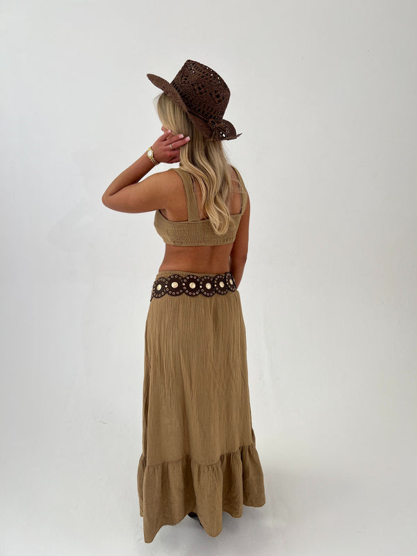 Woman wearing a camel top and skirt with a hat on a white background