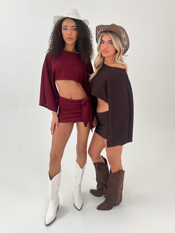 Lady in a burgundy outfit with white hat and boots Lady in a brown outfit with brown hat and boots on a white background