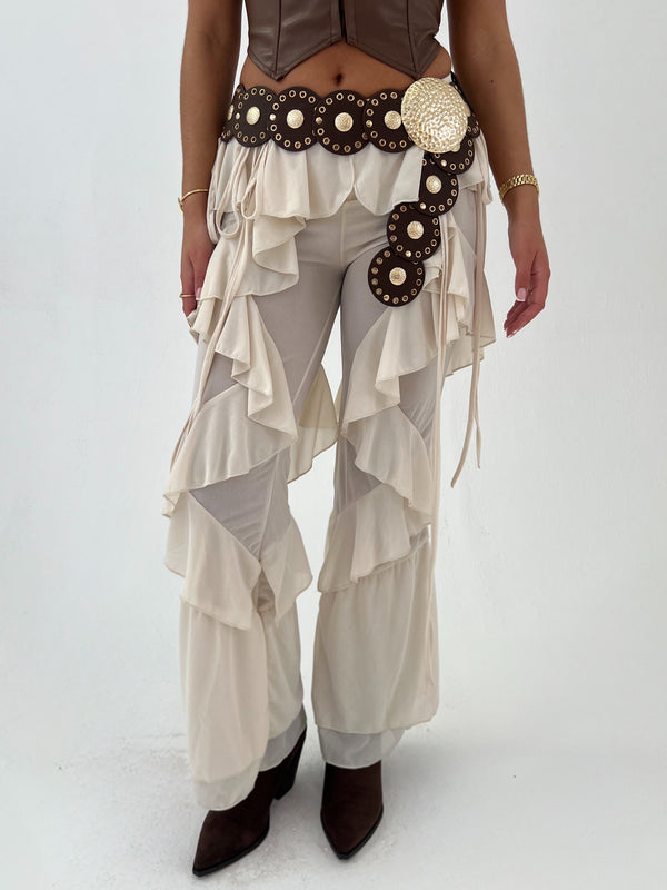 Person wearing a unique outfit with layered pants and decorative belt on a white background