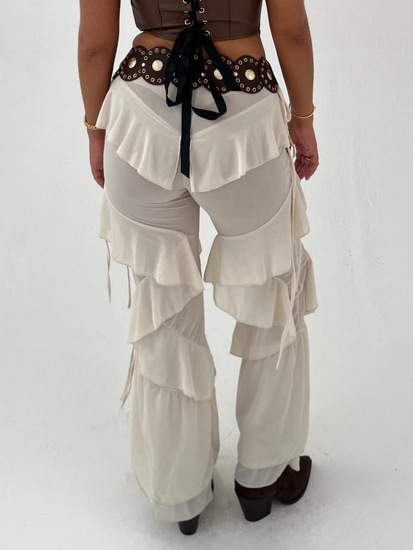 Person wearing a brown top and beige layered pants on a white background