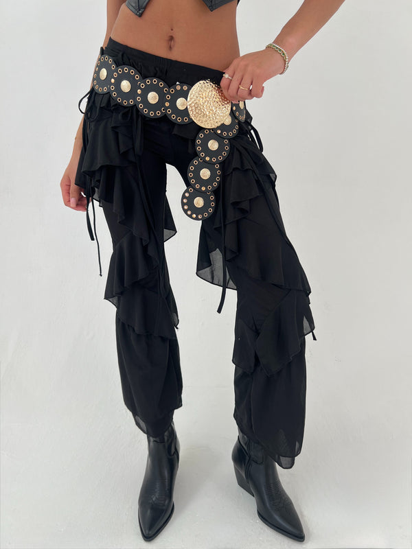 Black ruffled pants with decorative elements on a white background