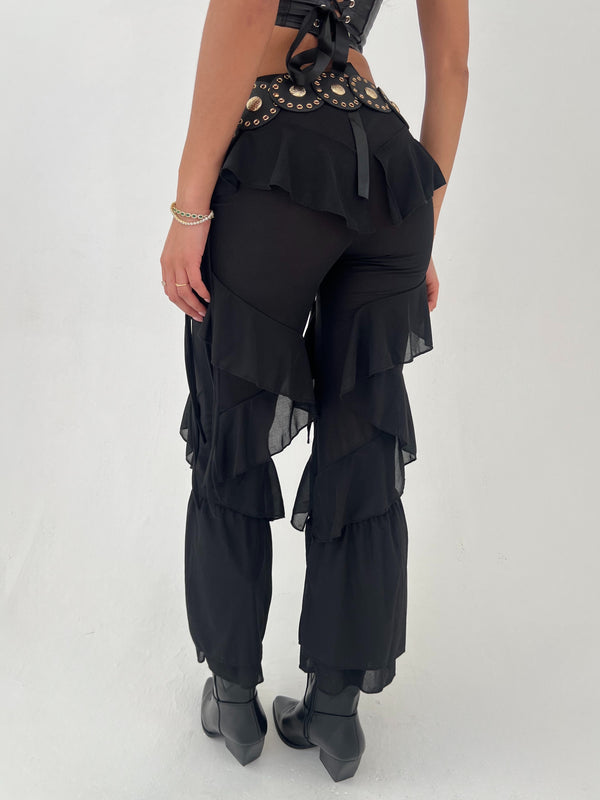 Black layered trousers with embellishments on a white background