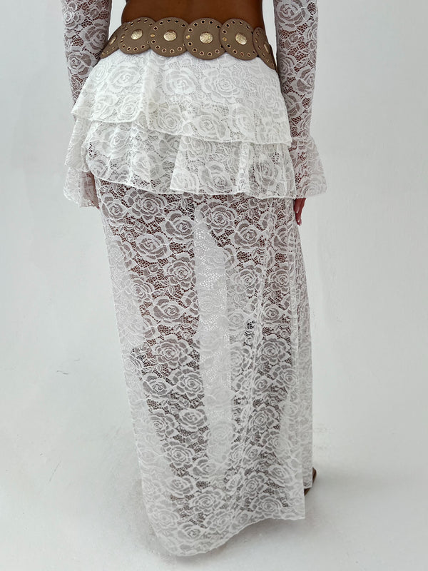 Woman wearing a white lace outfit with gold accents on a white background