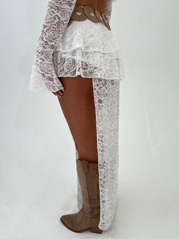 Woman wearing a white lace outfit with gold accents on a white background