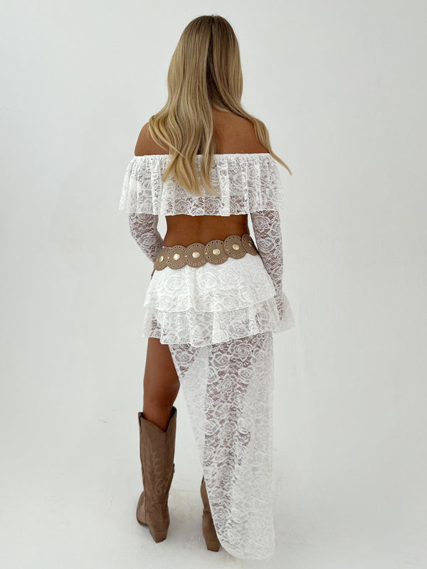 Woman wearing a white lace outfit with gold accents on a white background