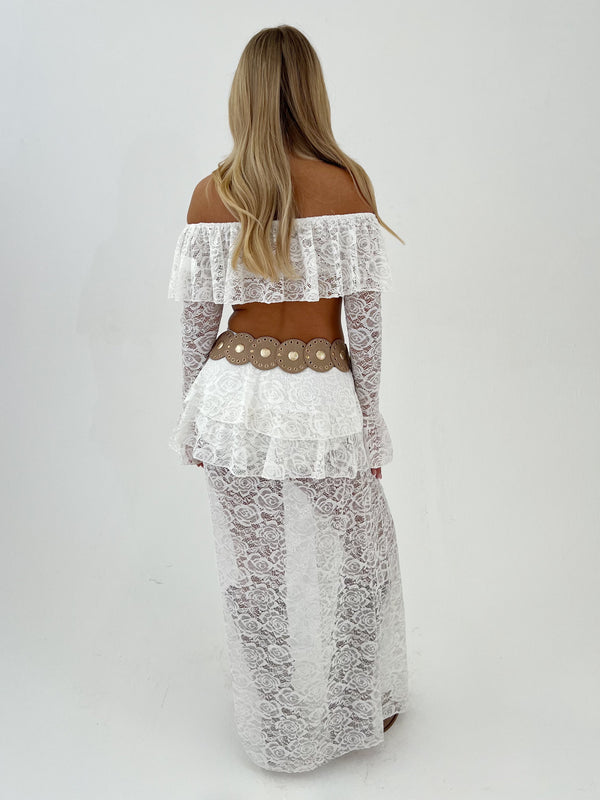 Lady in white top and skirt with a beige belt on a white background