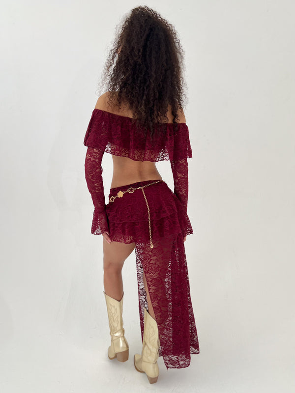 Lady wearing a burgundy outfit and gold belt and boots on a white background