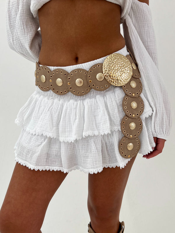 White skirt with a decorative gold belt on a plain background