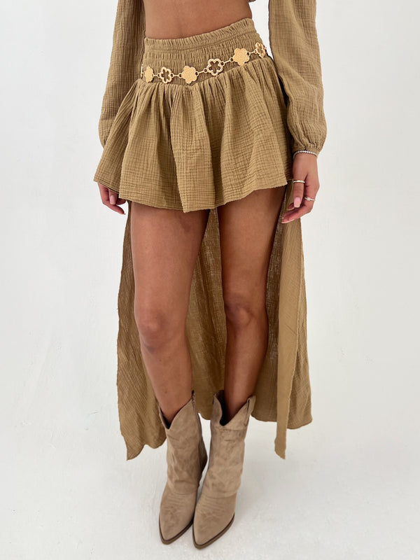 Person wearing a long camel skirt with a skirt and boots on a white background