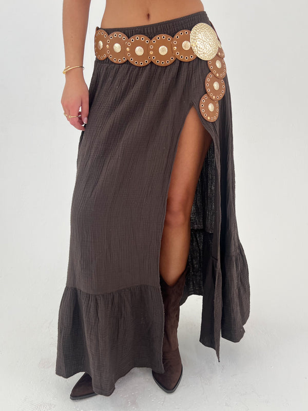 women in a brown skirt with belt and boots on a white background