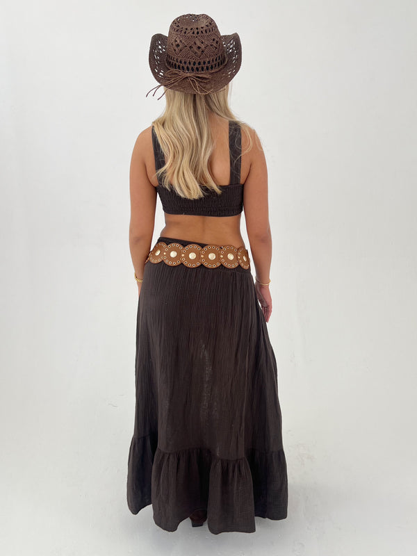 Woman wearing a brown cowboy hat and matching outfit on a white 