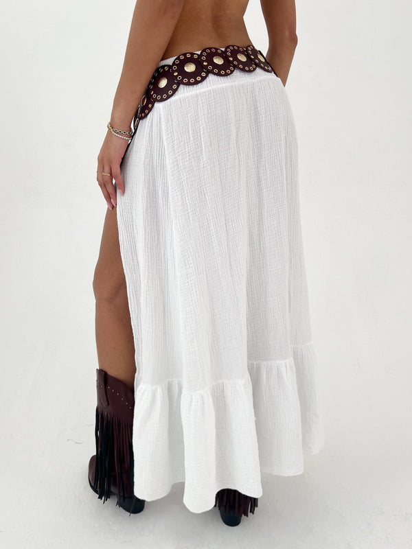 Woman wearing a white skirt , burgundy belt, and cowboy boots on a white background