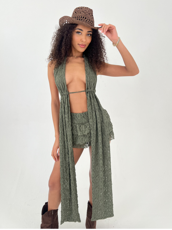 Woman wearing a green halter top and skirt with a cowboy hat on a white background