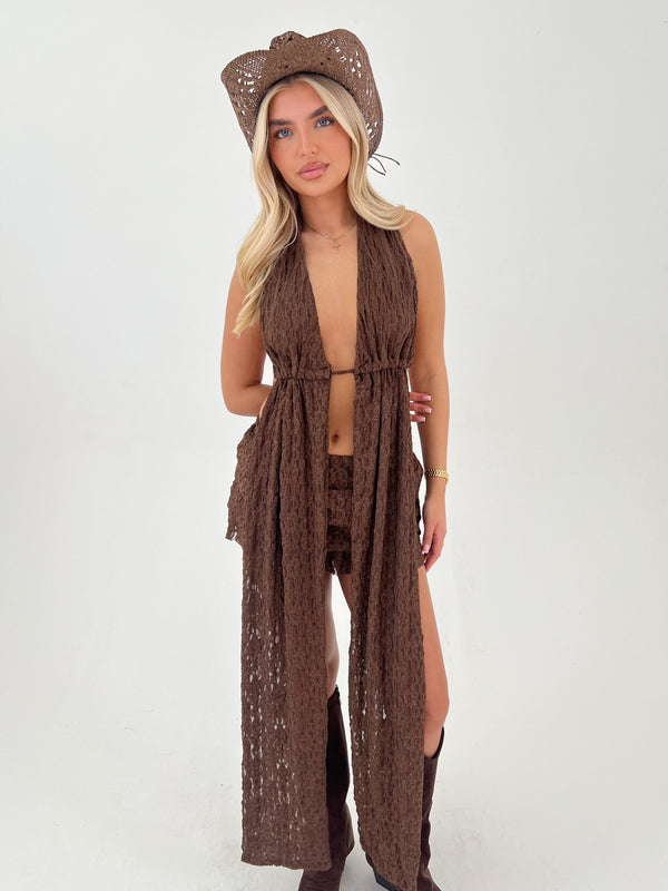 Woman wearing a brown crochet outfit with a matching hat on a white background