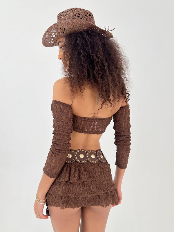Woman wearing a brown outfit with a matching cowboy hat on a white background