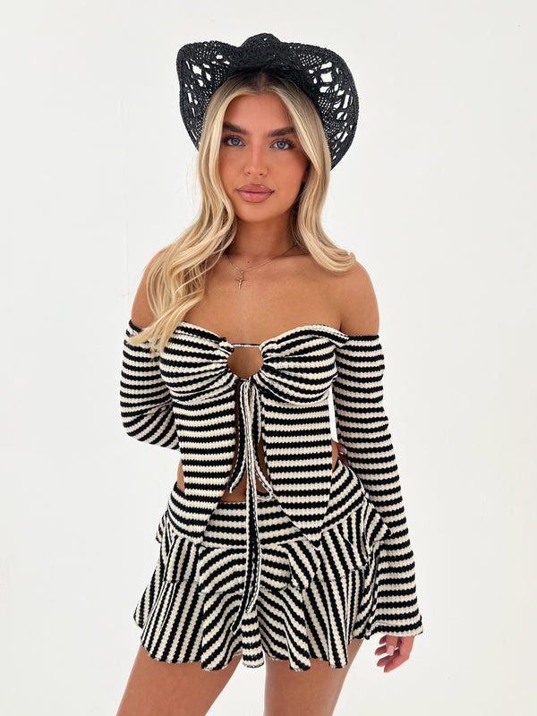 Woman wearing a black and white striped outfit with a black hat on a white background