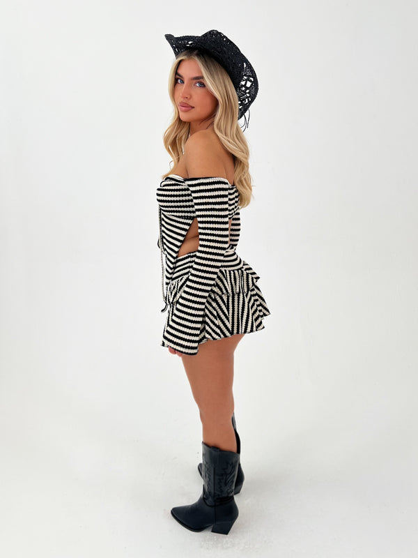 Woman wearing a black and white striped outfit and a black cowboy hat on a white background