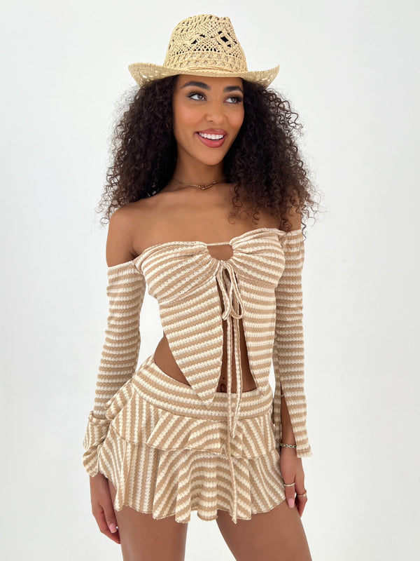 Woman wearing a beige and white striped outfit with a matching hat on a white background