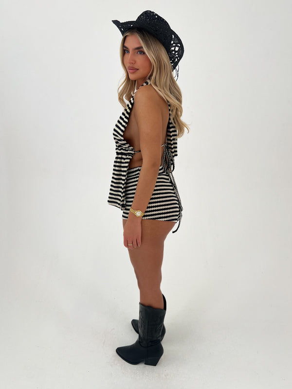 Woman wearing a black and white striped outfit with a cowboy hat on a white background