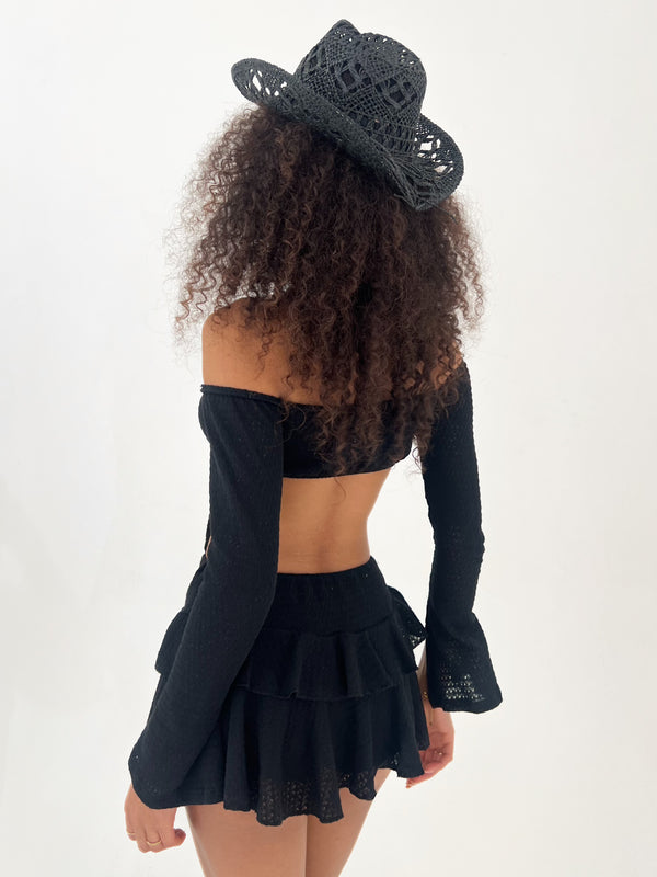 Person wearing a black outfit with a matching hat on a white background